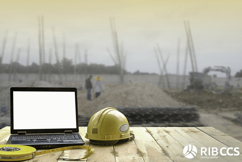 Hard hat and laptop in front of construction site