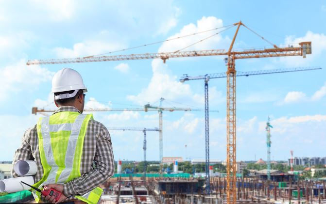 man looking at construction cranes